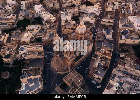 Veduta aerea della rotonda della chiesa di San Giovanni Battista tra edifici storici in pietra e tetti, Dingli, Malta. Foto Stock