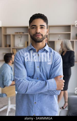 Ambizioso giovane uomo d'affari che guarda la macchina fotografica con le braccia incrociate Foto Stock