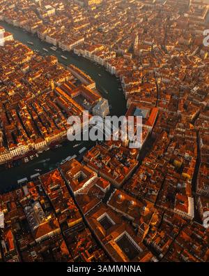 Vista aerea dello storico ponte di rialto sul Canal grande con pittoreschi edifici della città vecchia e tetti illuminati dal sole, Venezia, Italia. Foto Stock
