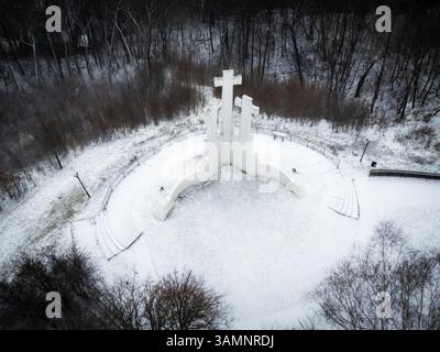 Vista aerea del monumento a tre croci circondato da una foresta innevata e da un tranquillo paesaggio, Vilnius, Lituania. Foto Stock