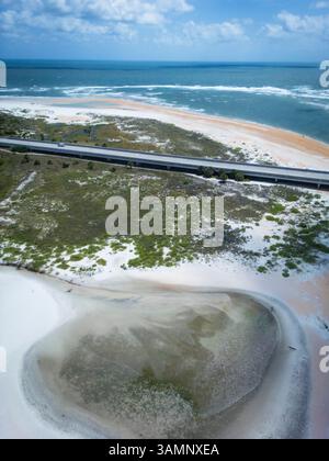 Vista aerea di motivi astratti e colori durante la bassa marea su Crescent Beach con un ponte sullo sfondo, St. Augustine, Stati Uniti. Foto Stock