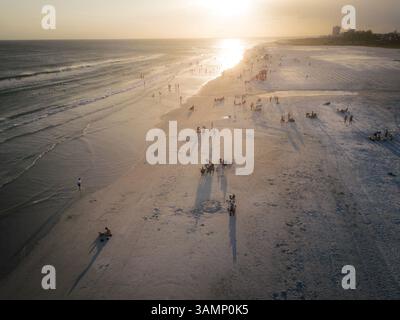 Vista aerea dello splendido tramonto sulla spiaggia con persone che camminano sulla spiaggia sabbiosa di Siesta Key, Stati Uniti. Foto Stock