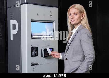 Donna che paga il costo del parcheggio utilizzando la carta di credito della macchina automatica Foto Stock