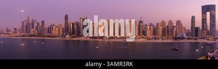 Vista aerea panoramica dello skyline del porticciolo di Dubai con alti grattacieli di fronte al torrente al tramonto, Dubai, Emirati Arabi Uniti. Foto Stock