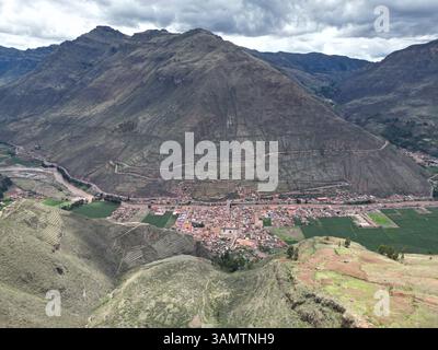 Vista aerea del pittoresco parco archeologico con villaggio tradizionale, campi verdi e maestose montagne, Pisac, Cusco, Perù. Foto Stock