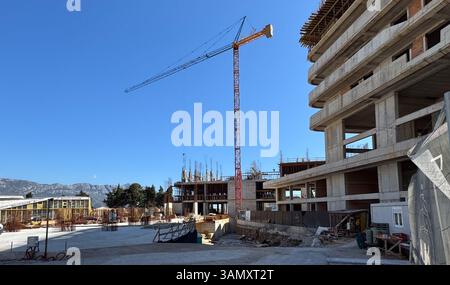 Budva, Montenegro, 11 aprile 2025: Un cantiere con una gru a torre e una struttura in cemento a più piani parzialmente costruita sotto un cielo azzurro. Foto Stock