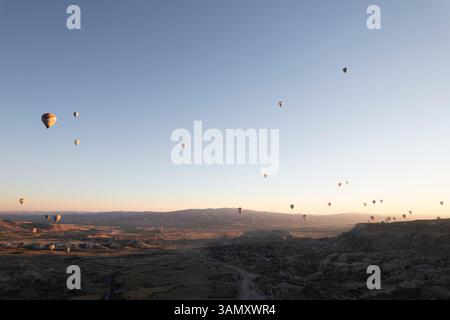 Vista aerea delle mongolfiere che si innalzano su una valle panoramica con camini delle fate all'alba, Goreme, Turchia. Foto Stock