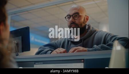 Young Man al banco check-in dell'aeroporto: Agente di linea aerea donna che controlla i documenti, consegna del passaporto e del pass d'imbarco al passeggero. Servizio clienti e check-in dei passaporti presso il terminal dell'aeroporto internazionale. Foto Stock