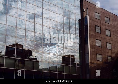 Un edificio commerciale con pannelli di vetro che riflettono il cielo. Foto Stock