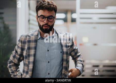 Uomo d'affari in ufficio che adatta il suo blazer a quadri con un'espressione mirata Foto Stock
