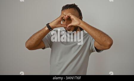 Il giovane uomo con trecce e barba dà forma al cuore con le mani su sfondo bianco che sfoggiano un'espressione felice e un abbigliamento casual Foto Stock