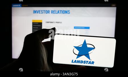 Stoccarda, Germania - 11-28-2024: Persona che possiede un telefono cellulare con il logo della società di trasporti statunitense Landstar System Inc. Sullo schermo Foto Stock