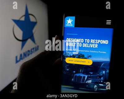 Stoccarda, Germania - 11-28-2024: Persona che detiene il cellulare con pagina web della società di trasporti statunitense Landstar System Inc. Su schermo con logo. Foto Stock