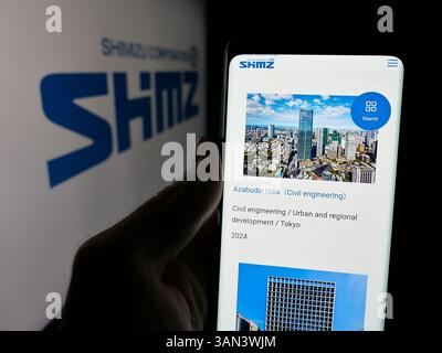 Stoccarda, Germania - 12-03-2024: Persona che detiene il cellulare con pagina web della società giapponese di ingegneria Shimizu Corporation sullo schermo con logo. Foto Stock