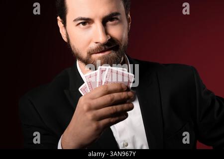 Bel giovane con carte da gioco per il poker su sfondo rosso Foto Stock