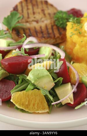 Maiale con zucca e insalata di arancia e barbabietole e avocado Foto Stock