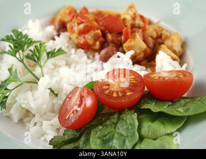 Stufato speziato di lenticchie di pollo e pepe con riso e insalata fresca Foto Stock
