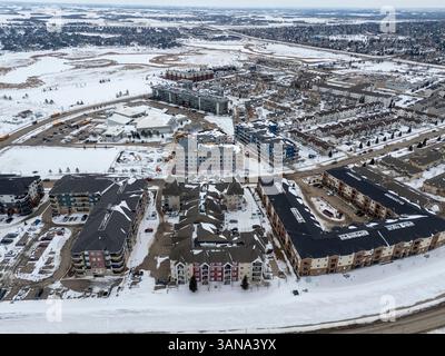 Paesaggio urbano innevato con un grande complesso di appartamenti nel centro. Gli edifici sono per lo più rossi e bianchi Foto Stock
