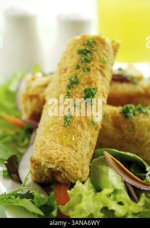 Panini di mais vegetariani cotti con burro di prezzemolo su un letto di lattuga mista Foto Stock