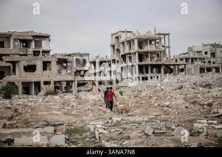 Damasco, Siria. 29 marzo 2025. Due uomini camminano attraverso un cimitero nel campo di Yarmouk, in gran parte distrutto. I residenti stanno lentamente tornando al campo di Yarmouk, a Damasco, dopo la caduta del regime di Assad lo scorso dicembre. (Credit Image: © Sally Hayden/SOPA Images via ZUMA Press Wire) SOLO PER USO EDITORIALE! Non per USO commerciale! Foto Stock
