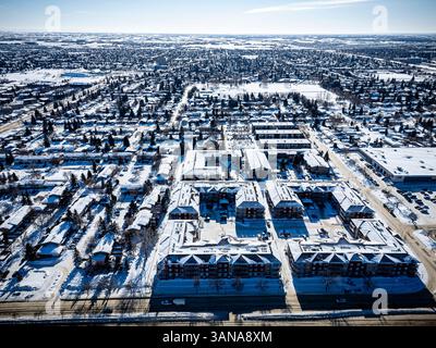 Paesaggio urbano innevato con un grande complesso di appartamenti nel centro. Il cielo è limpido e la neve copre il terreno Foto Stock