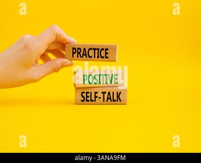 Esercitarsi con il simbolo di autoapprendimento positivo. Le parole concettuali esercitano un'autocomunicazione positiva su blocchi di legno. Mano d'affari. Bellissimo sfondo giallo. Affari Foto Stock