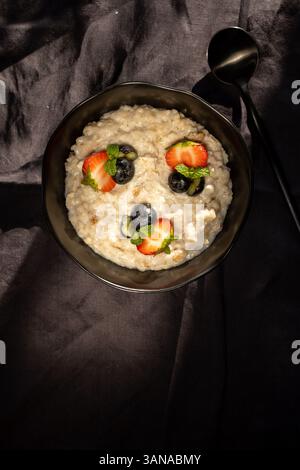 Porridge di farina d'avena con fragole e mirtilli e semi di chia su sfondo nero Foto Stock