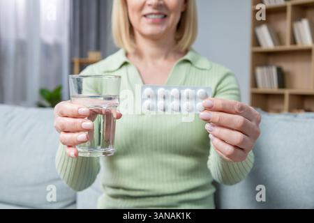 Donna bionda di 50 anni che prende pillole ormonali sostitutive Foto Stock