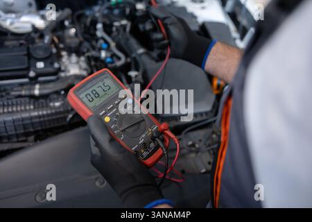 Riparazione specializzata misurazione carica batteria con voltmetro per l'assistenza diagnostica Foto Stock
