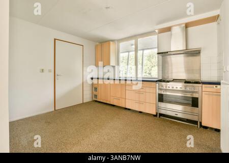 Una cucina moderna, spaziosa e ben illuminata, con eleganti mobili, elettrodomestici in acciaio inossidabile e un design minimalista per cucinare e cenare in modo efficiente. Foto Stock