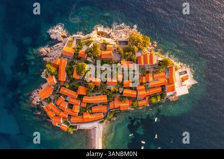 Vista aerea della pittoresca isola di Sveti Stefan con edifici storici e costa rocciosa al tramonto, Budva, Montenegro. Foto Stock