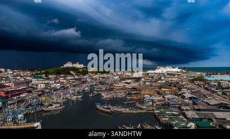 Vista aerea di un porto tempestoso con barche ed edifici in un villaggio di pescatori, Elmina, Ghana. Foto Stock