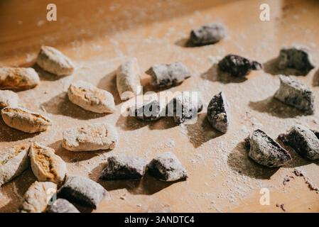 Una tavola coperta da vari tipi di ciambelle, tra cui alcune con zucchero a velo. Le ciambelle sono distribuite in forme e dimensioni diverse, Foto Stock