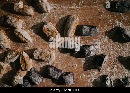 Un tavolo coperto di vari tipi di ciambelle, tra cui alcune con glassa blu. Le ciambelle sono sparse sul tavolo, alcune più vicine al fron Foto Stock