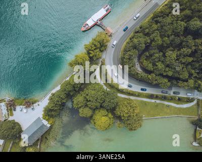 Vista aerea del lago Annecy con Chateau de Duingt, costa tranquilla e strada curva circondata dal verde, Duingt, Francia. Foto Stock