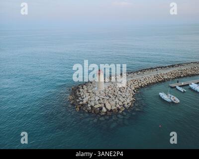 Veduta aerea dello splendido faro sulla frangiflutti di Mentone con oceano tranquillo e barche, Mentone, Francia. Foto Stock