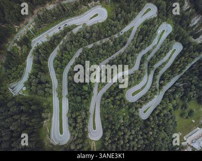 Vista aerea del tortuoso passo della montagna SS26 attraverso la lussureggiante foresta verde e le maestose montagne, Pre-Saint-Didier, Italia. Foto Stock