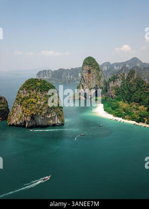 Vista aerea di piccole imbarcazioni veloci che esplorano le gigantesche scogliere calcaree e le isole nel mare blu turchese, un paradiso tropicale, Phra Nang, Krabi, Phu Foto Stock