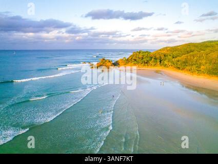Vista aerea del passo in Byron Bay al tramonto, nel nuovo Galles del Sud Australia. I surfisti stanno catturando le loro ultime onde e il cielo è pieno di wi Foto Stock