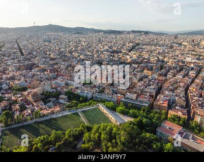 Vista aerea del vivace paesaggio urbano con edifici residenziali, verde e un campo da calcio, Sants-Montjuic, Barcellona, Spagna. Foto Stock