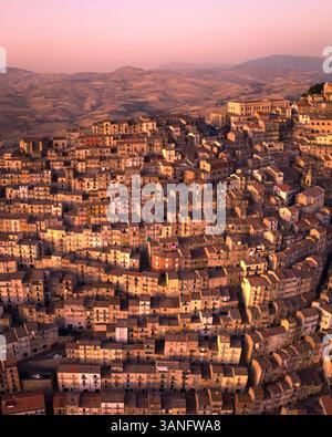 Vista aerea della pittoresca città vecchia con case affascinanti e uno sfondo di montagna al tramonto, Gangi, Italia. Foto Stock