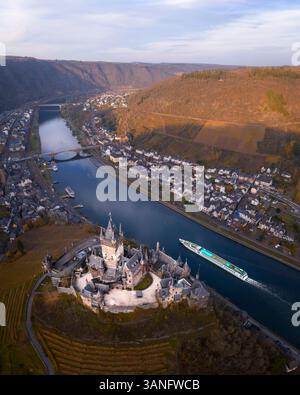 Vista aerea del pittoresco castello medievale di Reichsburg che si affaccia sul tranquillo fiume Mosella con colline autunnali e un'affascinante città, Cochem, Germania. Foto Stock
