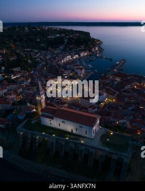 Vista aerea del borgo medievale con chiesa e paesaggio costiero al tramonto, Pirano, Slovenia. Foto Stock