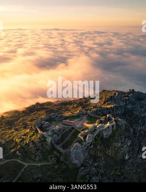 Vista aerea del pittoresco villaggio con nuvole e montagne all'alba, Monsanto, Portogallo. Foto Stock