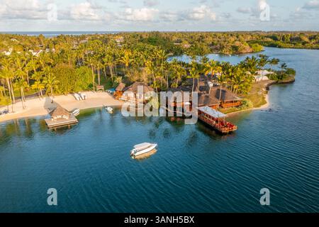Flacq, Mauritius - 28 settembre 2022: Veduta aerea di bungalow lungo la spiaggia di un resort di lusso con una piccola barca che si avvicina alla riva, Poste d Foto Stock