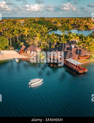 Flacq, Mauritius - 28 settembre 2022: Veduta aerea di bungalow lungo la spiaggia di un resort di lusso con una piccola barca che si avvicina alla riva, Poste d Foto Stock