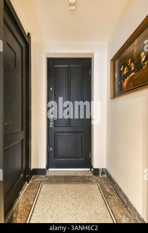 Un'entrata sofisticata caratterizzata da un'elegante porta nera, circondata da un pavimento in marmo e da belle pareti artistiche. Ideale per un design contemporaneo. Foto Stock