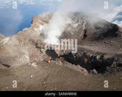 Veduta aerea di una persona in piedi che guarda sulla sporgenza del vulcano Gamalama a Ternate, Indonesia. Foto Stock