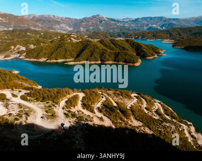Vista aerea del tranquillo lago di Bovilla circondato da maestose montagne e da una strada tortuosa, Herraj, Tirana, Albania. Foto Stock