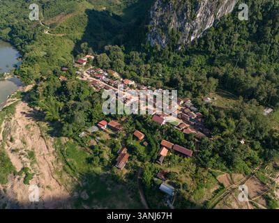 Vista aerea del villaggio sopjam con case tradizionali circondate da lussureggiante vegetazione e montagne, la provincia di Luang Prabang, Laos. Foto Stock